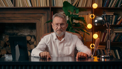 Confident successful old Caucasian man male mature takes off glasses looking at camera folded hands...