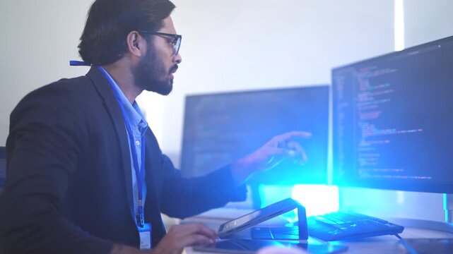 Focused Indian male AI developer coding a complex machine learning algorithm late at night. A dedicated data scientist working on a neural network at a multi-monitor workstation.