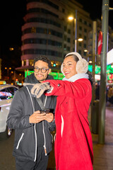 Tourists using gps on smartphone and pointing at night city street