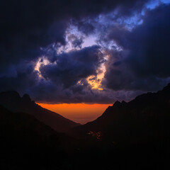 A landscape of a Corsican sunset with clouds and a colorful sky, creating a mystical and captivating atmosphere. The contrasts between moonlight and cloud shadows add a dramatic touch.

