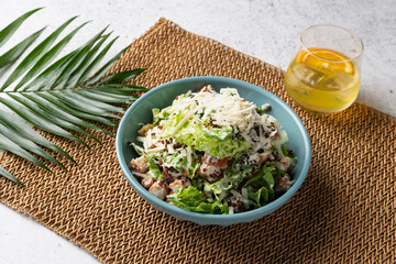 Caesar salad with chicken, grated parmesan, and croutons, served in a light blue bowl
