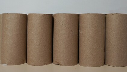 Cardboard bushings.Five empty cardboard toilet paper tubes standing in a row on a light background. They are suitable for recycling, creativity, children's crafts and space organization.