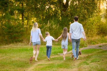 Mom, dad, boy, girl enjoying country vacation, holding hands, running barefoot on grass, jumping...