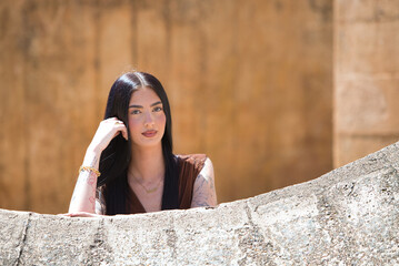 A young, beautiful brunette woman with long hair rests her cheek on her hand and looks thoughtful...