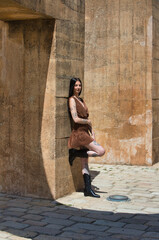 Latin woman, young and pretty brunette with tattoos on her arms and legs, wearing a brown dress and...