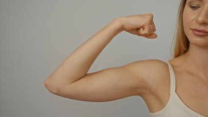 Woman flexing her arm showcasing strength and fitness over isolated white background evoking health and empowerment concepts with clear modern aesthetic.