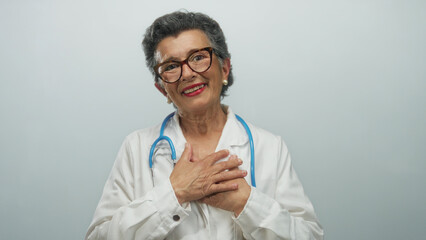 Senior woman doctor with grey hair and glasses wearing stethoscope and white coat smiling warmly...