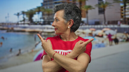 Senior woman with grey hair in volunteer shirt joyfully points in opposite directions on a lively...