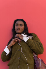 Young model listening to music on a pink background.