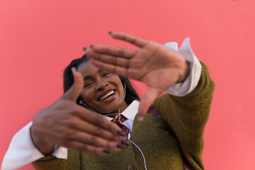Cheerful young girl framing her face with her hands isolated on a pink background