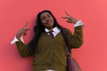 Young stylish showing peace sign with both hands and smiling