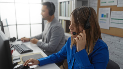 Woman and man working at office desks using headsets demonstrating effective teamwork in a modern...