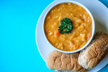 A Bowl Of Lentil Soup Garnished With Parsley Served With Wholemeal Submarine Brown Rolls