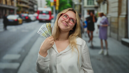 Fototapeta premium Young woman with glasses smiling and holding romanian currency on a busy city street creates a vibrant scene blending wealth and urban life outdoors.