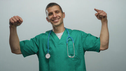 Naklejka premium Man in green doctor uniform with stethoscope smiling against white isolated background showcasing medical professionalism and positivity.