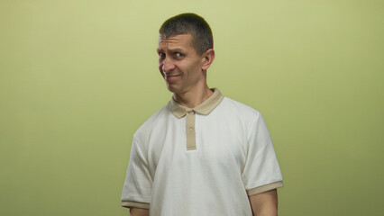Man expressing confusion standing against plain yellow background in casual white shirt with short...