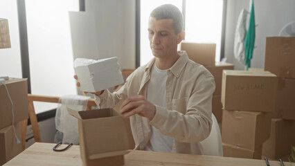Man unpacking in a new home, surrounded by boxes in a bright living room, carefully arranging items...