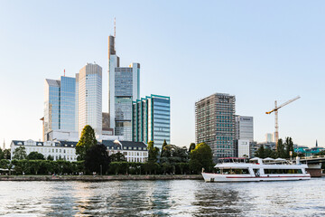 A Frankfurt city skyline in Germany with a large building in the middle the water Main river is calm and the sky is clear
