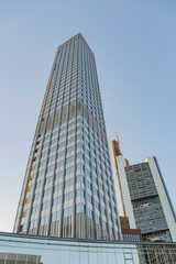 A Frankfurt city skyline in Germany with a tall building in the middle the sky is clear and the sun...