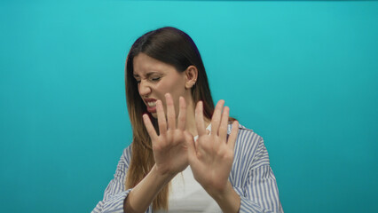 Young hispanic woman wearing striped shirt and white top showing palms in studio; disgust revulsion...