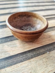 Rustic wooden bowl on striped surface presents a natural, earthy still life with subtle textures and minimalist composition