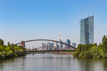 Naklejka premium View of the Frankfurt skyline in Germany across the iron railway bridge from the Main River on the right you can see a tall glass building in the port park.