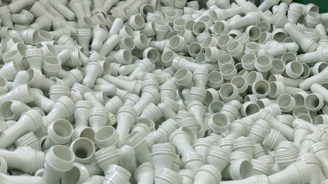 A pile of preforms for making plastic bottles. Blank for the production of containers. Conveyor belt deliver the preform shape to the  blow mold machine.The operation of plastic bottle blowing machine