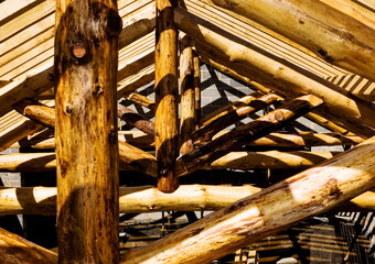 Close-up of a wooden structure's beams and supports, possibly a roof or frame, with sunlight casting shadows.