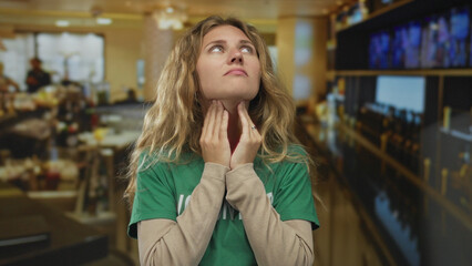 Woman clutching neck while choking at bar appears as a blonde young subject in pain and with a...
