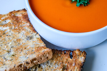 A Bowl Of Healthy Tomato Soup With Parsley Garnish And Toast