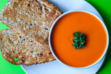 A Bowl Of Healthy Tomato Soup With Parsley Garnish And Toast