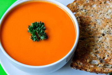 A Bowl Of Healthy Tomato Soup With Parsley Garnish And Toast