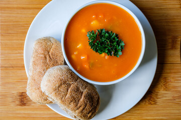 A Bowl Of Healthy Vegetable Soup Garnished With Parsley And Wholemeal Brown Submarine Bread Rolls