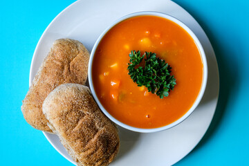 A Bowl Of Healthy Vegetable Soup Garnished With Parsley And Wholemeal Brown Submarine Bread Rolls