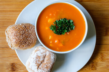 A Bowl Of Healthy Vegetable Soup Garnished With Parsley And Soft Bread Rolls