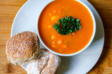 A Bowl Of Healthy Vegetable Soup Garnished With Parsley And Soft Bread Rolls