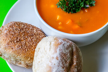 A Bowl Of Healthy Vegetable Soup Garnished With Parsley And Soft Bread Rolls