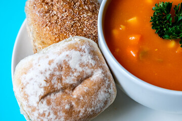 A Bowl Of Healthy Vegetable Soup Garnished With Parsley And Soft Bread Rolls