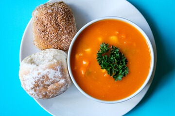 A Bowl Of Healthy Vegetable Soup Garnished With Parsley And Soft Bread Rolls