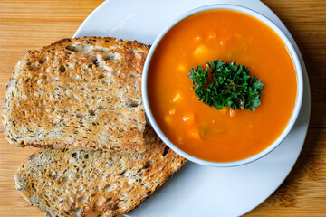 A Bowl Of Healthy Vegetable Soup Garnished With Parsley And Served With Toasted Bread