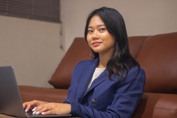 Asian business woman working from home using laptop wearing modern and stylish blazer