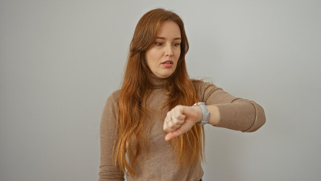 Woman checking smartwatch time against a clean white background, exhibiting modern technology interaction with neutral expression, highlighting casual lifestyle and fashion.