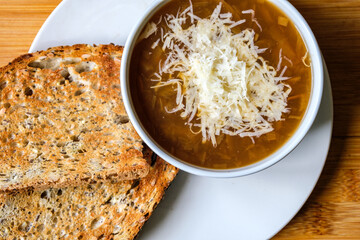 A Bowl Of Traditional French Onion Soup Topped With Grated Cheese And Toasted Bread