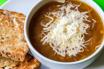 A Bowl Of Traditional French Onion Soup Topped With Grated Cheese And Toasted Bread