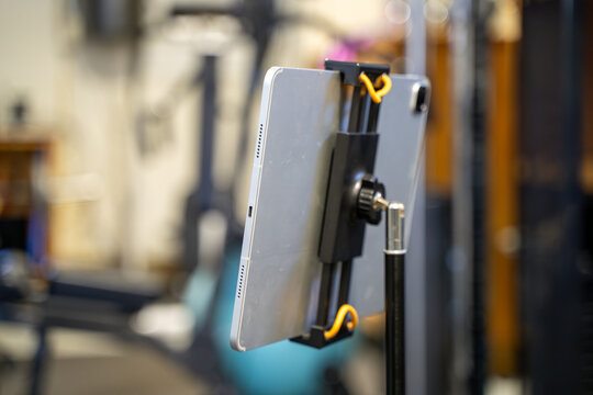 Close up of tablet showing online fitness class in gym.