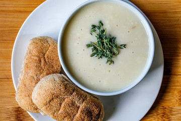 Bowl Of Chicken Soup With Thyme Garnish And Wholemeal Submarime Bread Rolls