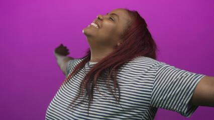 Woman stretching arms wide with a beaming smile, face turned upward and long red hair in a magenta...