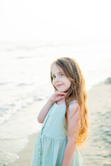 Portrait of a little girl near the sea at sunset. Child on the beach. Sea vacation.