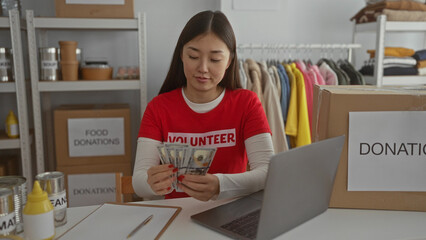 Woman counting american dollars in a charity donation center with food supplies organized on...