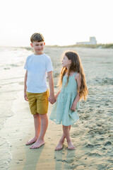 Little boy and girl near the sea at sunset. Children on the beach. Sea vacation.